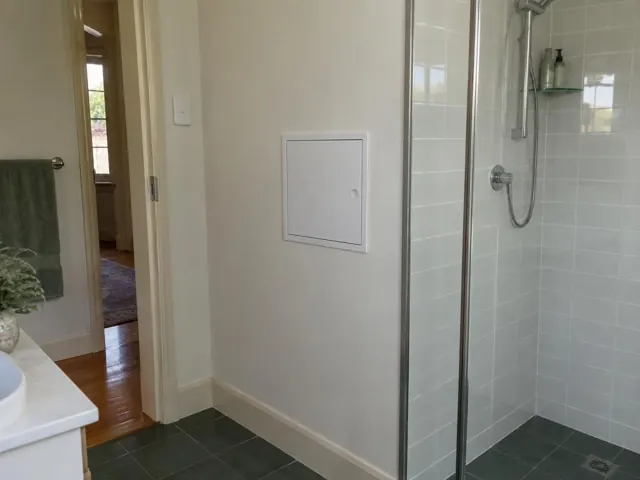 Neat access panel on a bathroom wall beside a tiled shower and vanity in Penshurst